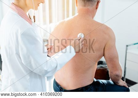 Doctor using stethoscope to check lung function on back of man