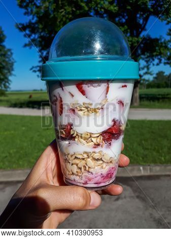 Hand Holding Healthy Breakfast Overnight Oats With Fresh Strawberries, Blueberries In A Plastic Cont