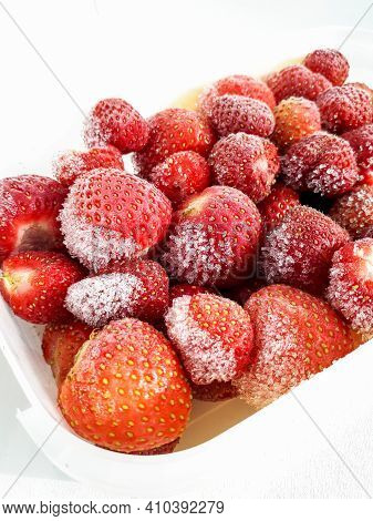 Macro Shot Of Frozen Strawberries With Frost On Them In A Plastic Container On White Background