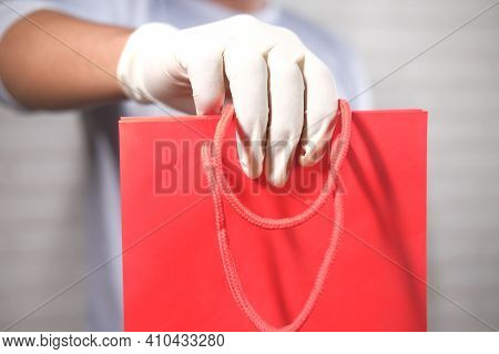 Hand In Latex Gloves Holding Red Color Shopping Bag On White Background