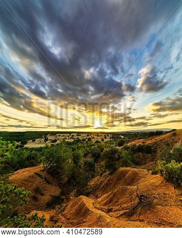 Sunset Landscape In The Field, Trees, Red Earth And Sky With Big Clouds In Blue And Orange Tones Of 