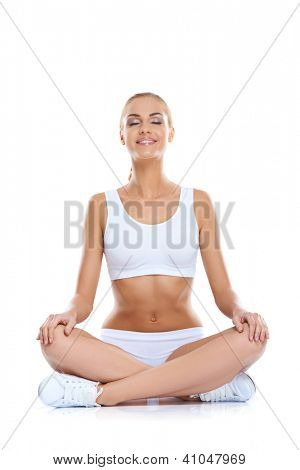 Klidný šťastná žena s pěknou postavu a holé břicho sedět se zkříženýma nohama na podlaze meditati