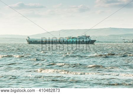 Sea Cargo Ferry In The Stormy Sea. Mountanious Background.