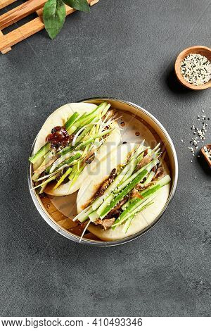Bao bun with roast duck. Bamboo steamer on dark slate table. Chinese, asian, authentic food concept.