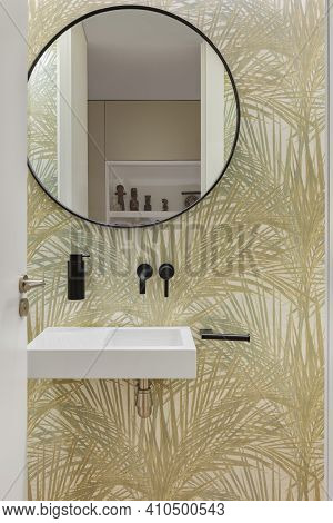 Bathroom With Wallpaper With Plant Leaves Texture, Small Wash Basin And Round Mirror. Minimalist Int