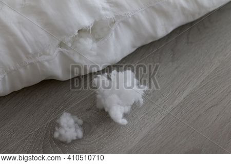 A Lump Of Pillow Filler Lies Next To A Torn Pillow On A Light Wooden Table. Close-up. Selective Focu
