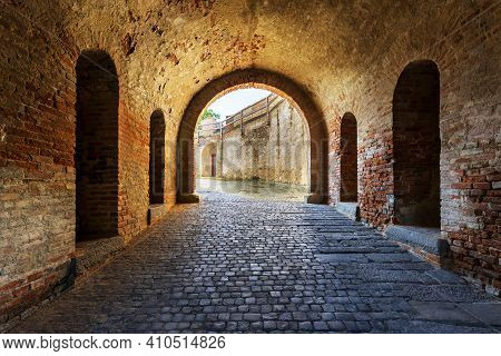 Passage Through The Tunnel. There Is An Old Brick Wall On The Sides. At The End Of The Tunnel Is A V