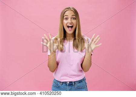 Amused And Surprised Excited Attractive Young Caucasian Female In Casual T-shirt Gesturing With Spre