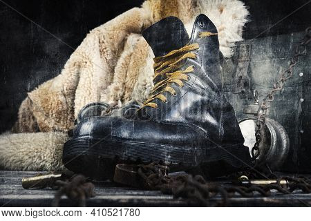 Leather Boot With Rusted Chains And Bullet Shells With Military Gas Mask And Fur Coat In Background