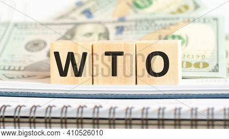 Wto. Wto Short For World Trade Organization. Business Concept On Wooden Cubes And Dollars Background