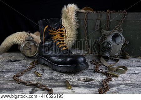 Leather Boot With Rusted Chains And Bullet Shells With Military Gas Mask And Fur Coat In Background