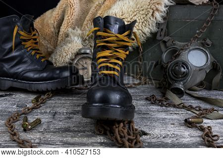 Leather Boots With Rusted Chains And Bullet Shells With Military Gas Mask And Fur Coat In Background
