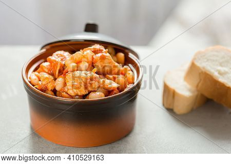 Pork Stew With White Beans In A Brown Bowl.