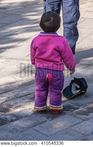 Beijing, China - April 29, 2010: Boy Toddler In Pink Vest And Purple Special Pants With Slit In Back