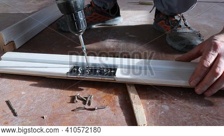 Tightening Screws With A Screwdriver Into The Fastening Holes On The Frame Of The Door Frame Located