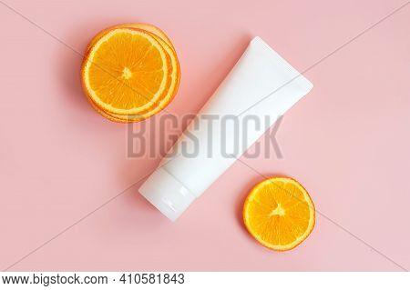 Cream Tube With Vitamin C Branding Concept And Orange Slices On Pink Background. Cosmetic Skincare P