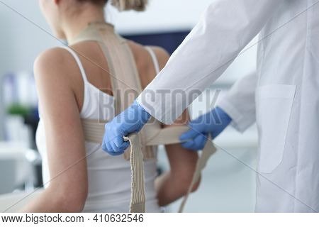 Doctor Putting Corset On Back Of Female Patient Closeup. Spinal Curvature Treatment Concept