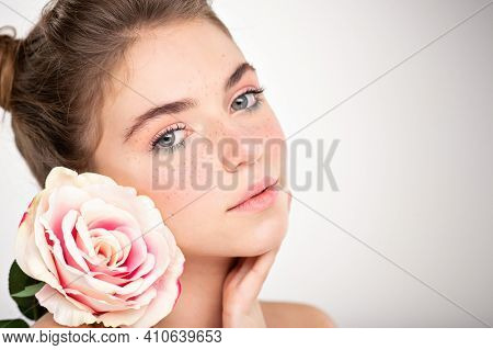 Beautiful young  woman with healthy skin face. Skin care concept. Closeup female face with a freckled. Women's face with flower Teenage girl with a clean skin of face, isolated.