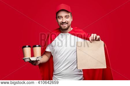 Happy Male Delivery Man In Red Cloak And Cap Demonstrating Paper Bag And Disposable Cups While Deliv