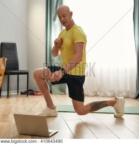 Trainer In Sportswear Doing Exercising At Home. Athletic Trainer In Uniform Doing Squatting At Home.