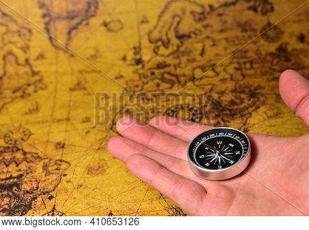 Compass In Hand On Map. Tourist Compass For Orientation On The Terrain. Magnetic Declination Alculat