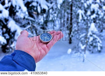 Compass In Hand On Snow Background. Orientation On The Terrain In The Forest In Winter Time. Map Rea