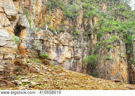 Small White Sculpture Of Christ With Open Arms Next To The Sedimentary Rock Walls Of Canyons Of Furn