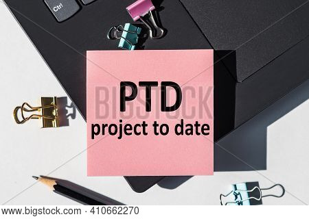 Ptd - Project To Date Acronym, Note Is Written On A Paper Sticker On A Laptop Keyboard.