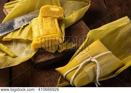 Pamonha, Brazilian Corn Food, Called Pamonha. On A Rustic Table With Knife And Old Corn Grater, Low