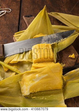 Pamonha, Brazilian Corn Food, Called Pamonha. On A Rustic Table With Knife And Old Corn Grater, Low