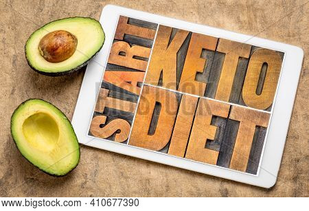 start keto diet, high fat ketogenic diet concept - word abstract in vintage letterpress wood type on a digital tablet with cut avocado