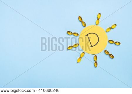 Vitamin D Concept, Nutritional Supplement And Health. Yellow Capsules In Form Of The Sun And Letter 