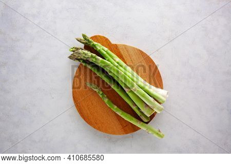 Bunch Of Asparagus On Wooden Cutting Board On Dark Gray And White Background.