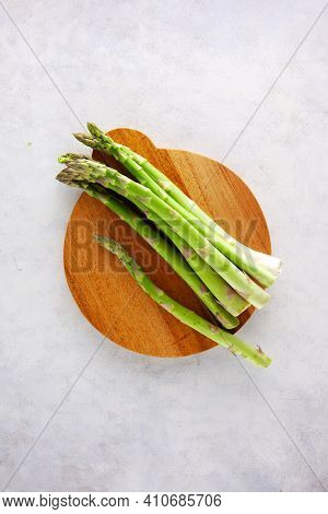 Bunch Of Asparagus On Wooden Cutting Board On Dark Gray And White Background.