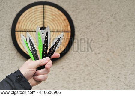 Throwing Knives. Sport And Hobby . Throwing Knives In A Mans Hand Close-up And A Target On The Wall.