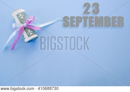 Calendar Date On Blue Background With Rolled Up Dollar Bills Pinned By Blue And Pink Ribbon With Cop