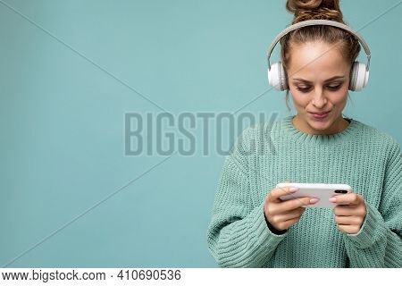 Closeup Portrait Photo Of Beautiful Positive Young Woman Wearing Blue Sweater Isolated Over Blue Bac