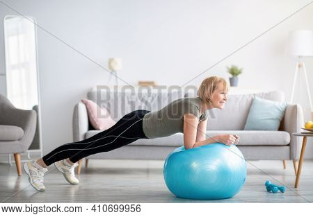 Domestic Sports During Covid-19 Concept. Athletic Mature Woman Standing In Plank On Fitness Ball, Wo