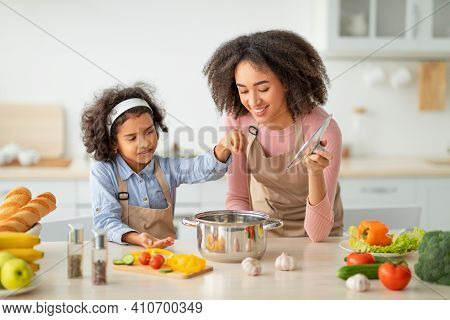 Bonding Concept. Cheerful African American Mother Helping Her Daughter To Cook, Teaching Little Girl