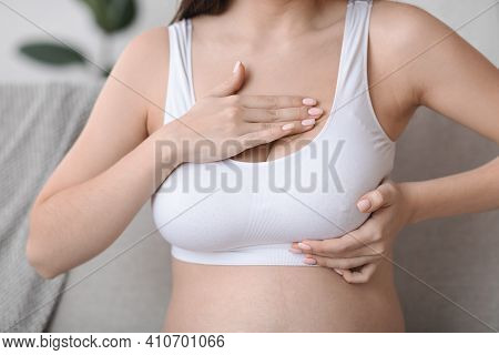 Body Changes During Pregnancy. Unrecognizable Pregnant Woman In Top Bra Massaging Breasts At Home, E