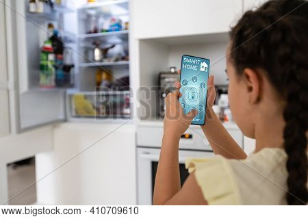 Shot Of Little Girl Using A Domotic System With Her Digital Tablet While Standing At Home.