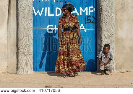 African Woman Coming Out Of The Gate Wild Camp Hostel When A Boy Poses In Front Of The Camera. 12 No