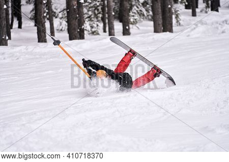 A Snowboarder Who Has Lost His Balance Does Not Let Go Of The Crossbar Of The Lift Bugel. He Rolls B