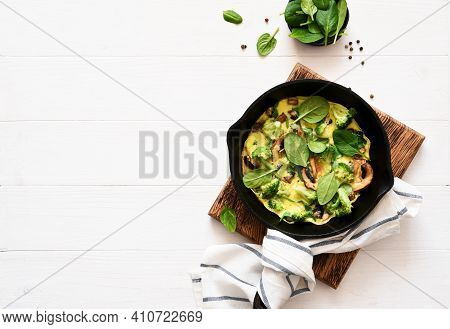 Omelet With Spinach And Mushrooms In A Cast-iron Pan On A Light Wood Background. Fritata With Spinac