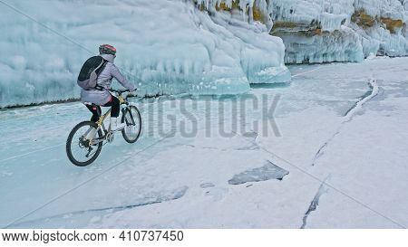 Woman Is Riding Bicycle Near The Ice Grotto. The Rock With Ice C