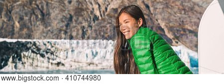 Alaska cruise travel tourist looking at inside passage Glacier Bay National Park. Banner of happy Asian woman enjoying sightseeing of USA vacation destination.