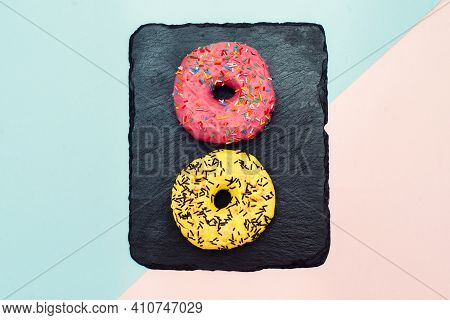 Colored Donuts With Colorful Sprinkles On Pink And Blue Background. National Pink Day Or Doughnut Da