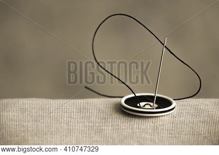 The Black And White Button Is Sewn With A Sewing Needle And Black Thread To Hold The Two Fabrics Tog