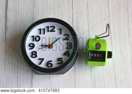 4 Digits Green Tally Counter Or Hand Counter With Alarm Clock On The Wooden Background