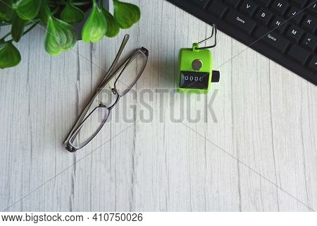 4 Digits Green Tally Counter Or Hand Counter With Glasses On The Wooden Background
